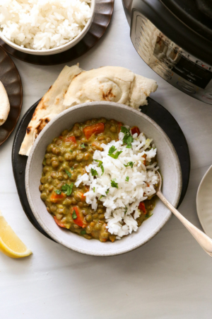 Instant Pot Lentil Curry served in a white bowl with rice and naan bread.