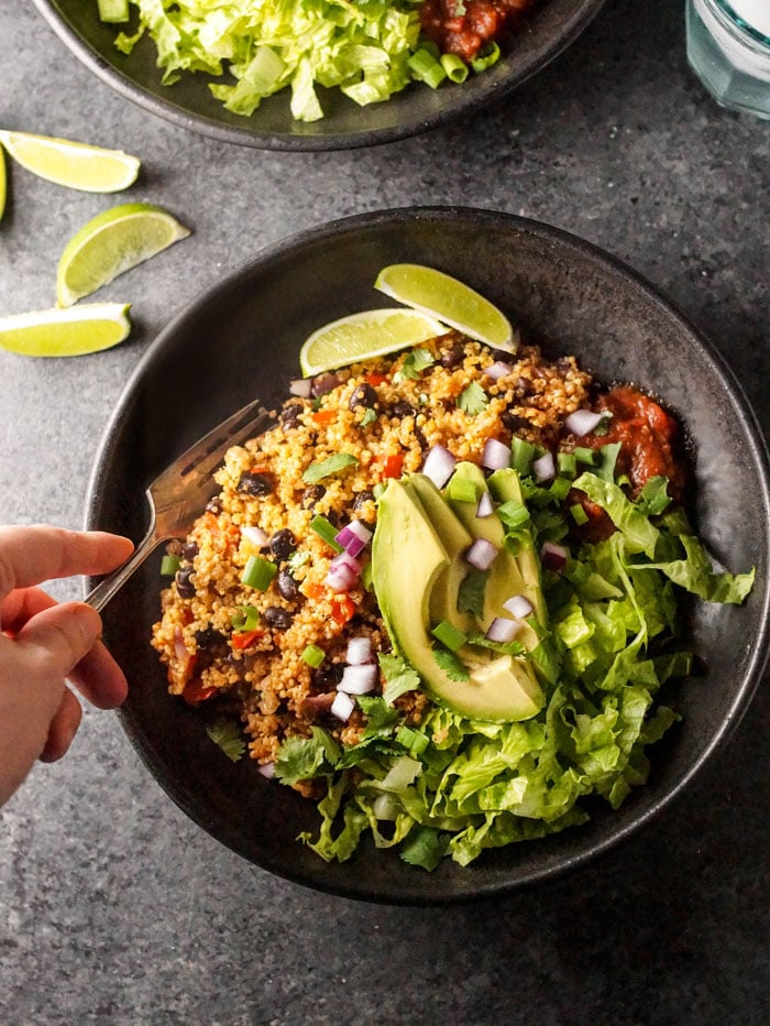  Vegan Quinoa Burrito Bowl with avocado, red onion, and lime slices on top