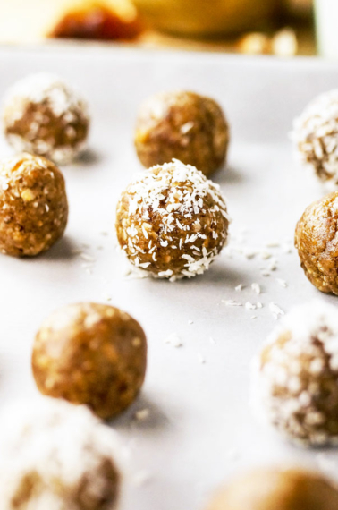 nut free date ball with half rolled in coconut on pan
