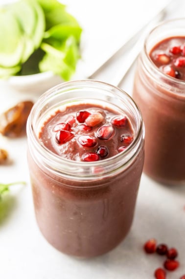 acai smoothies topped with pomegranate seeds in glass jar