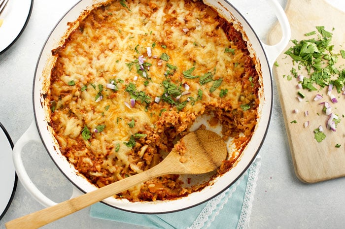 mexican cauliflower rice casserole in a pan with a wooden spoon