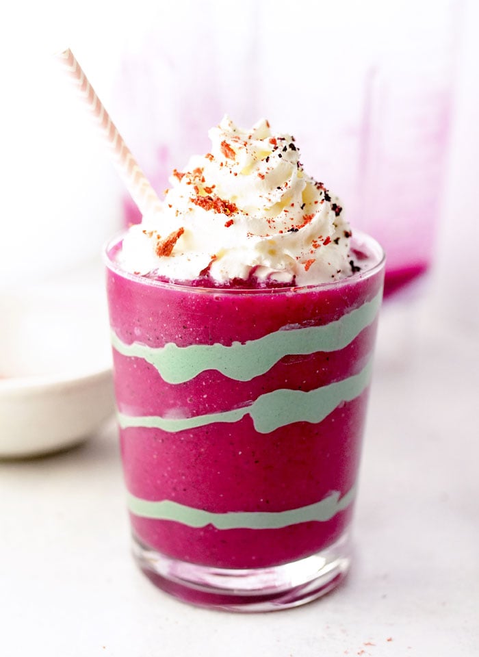 healthy unicorn smoothie in a glass with whipped cream and a straw