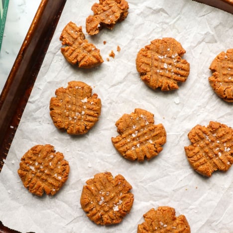 healthy peanut butter cookies on a baking sheet with salt.