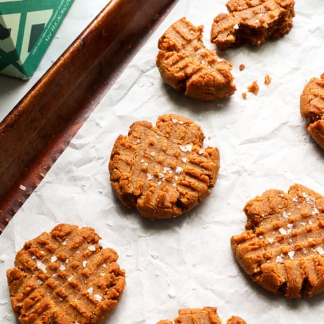 healthy peanut butter cookies topped with salt on a pan.