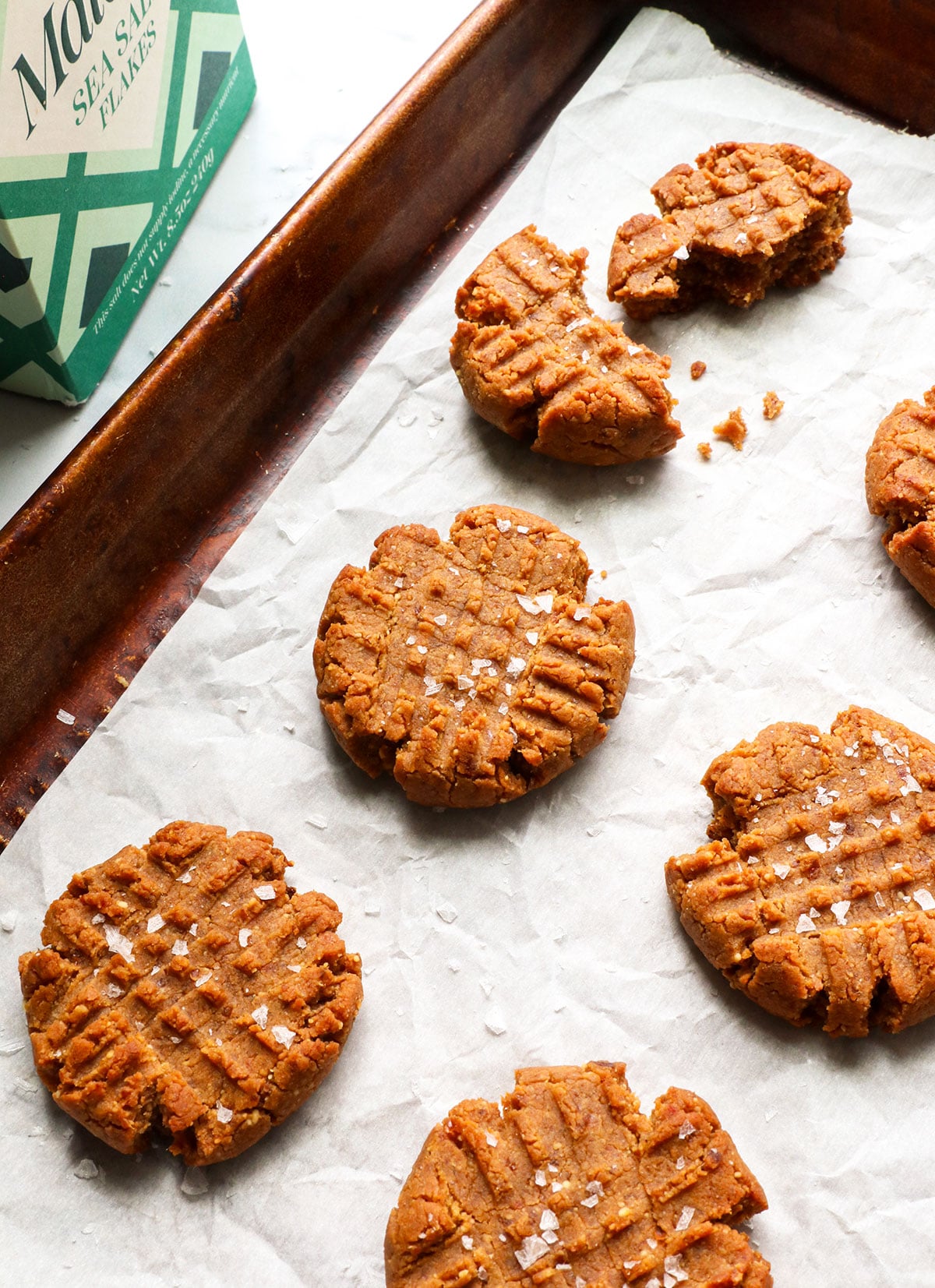 healthy peanut butter cookies topped with salt on a pan.