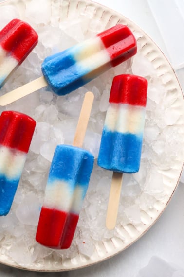 red white and blue popsicles on a plate with ice.
