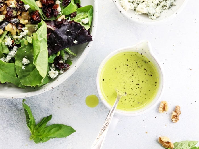 orange basil vinaigrette recipe with a spoon and a bowl of salad