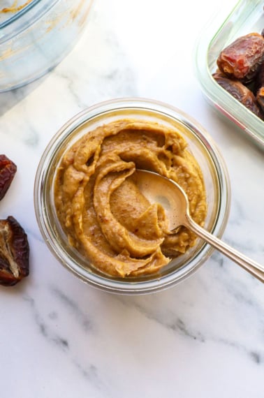 date paste stored in a glass jar with a spoon.