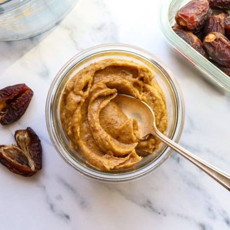 date paste stored in a glass jar with a spoon.