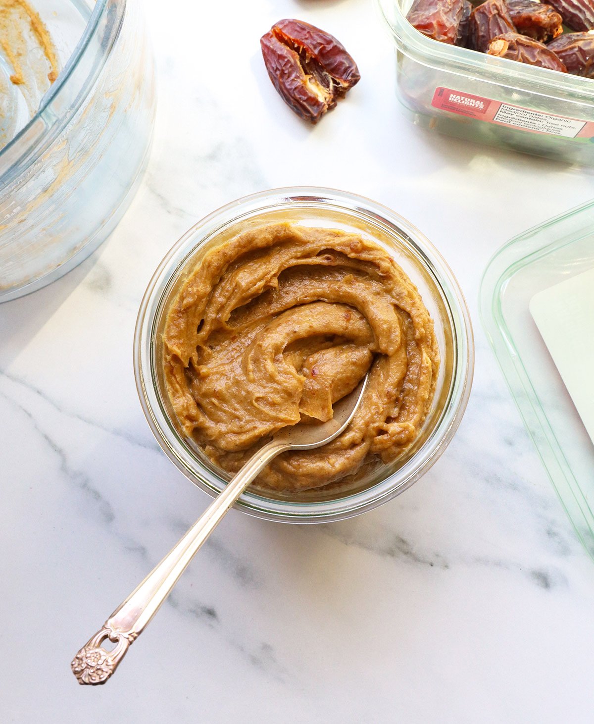 date paste in a glass jar with a spoon and dates nearby. 
