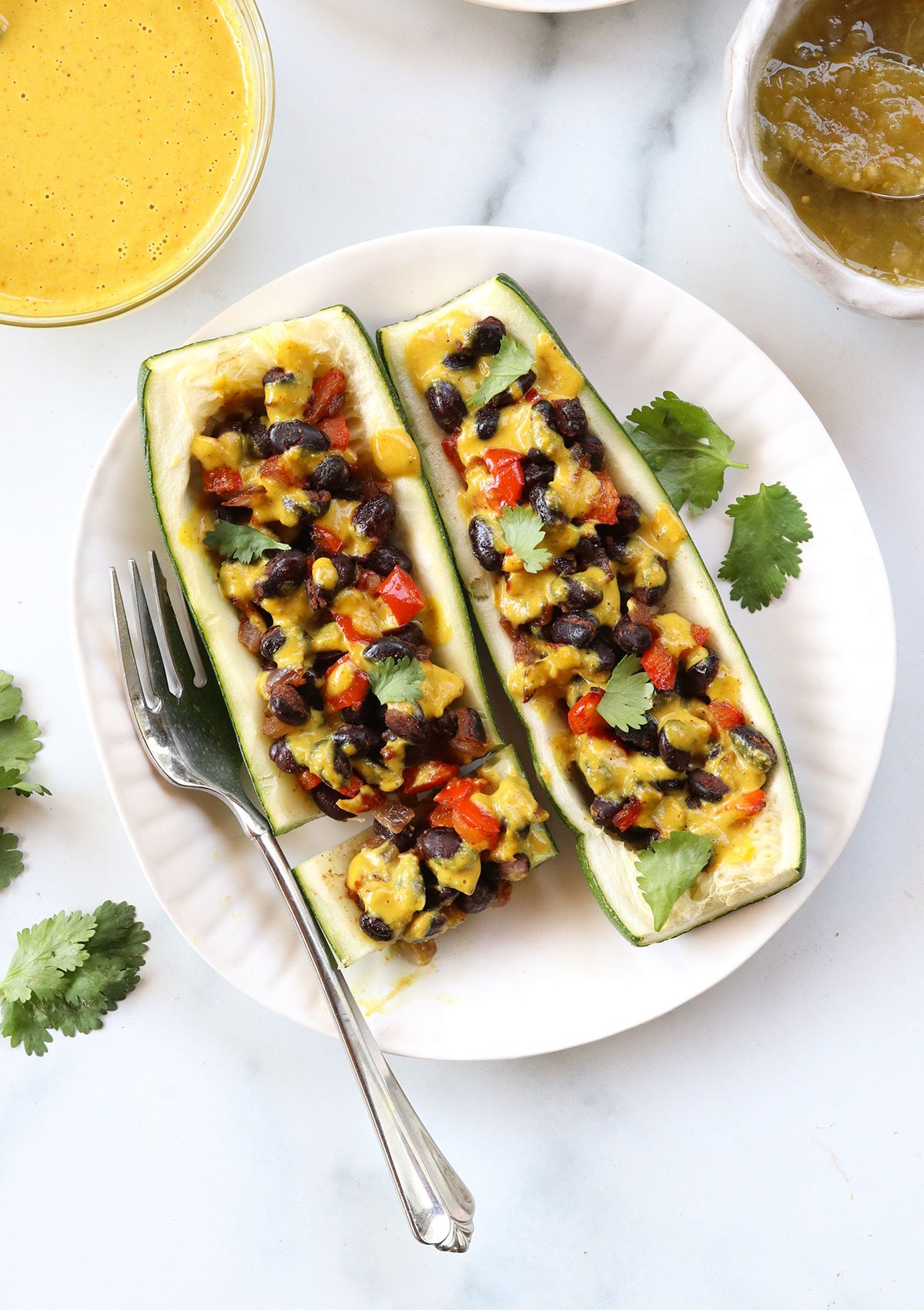 vegan stuffed zucchini boats on a white plate with a fork. 