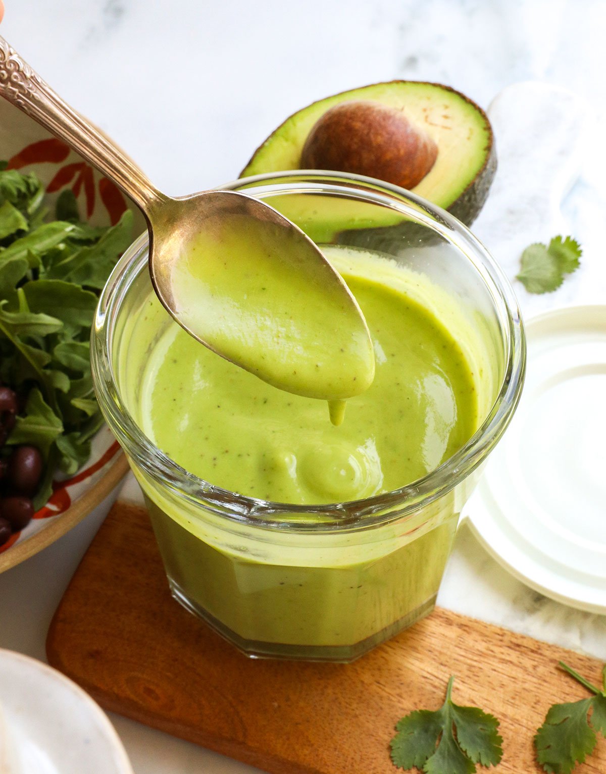 avocado dressing lifted on a spoon from a glass jar. - 5
