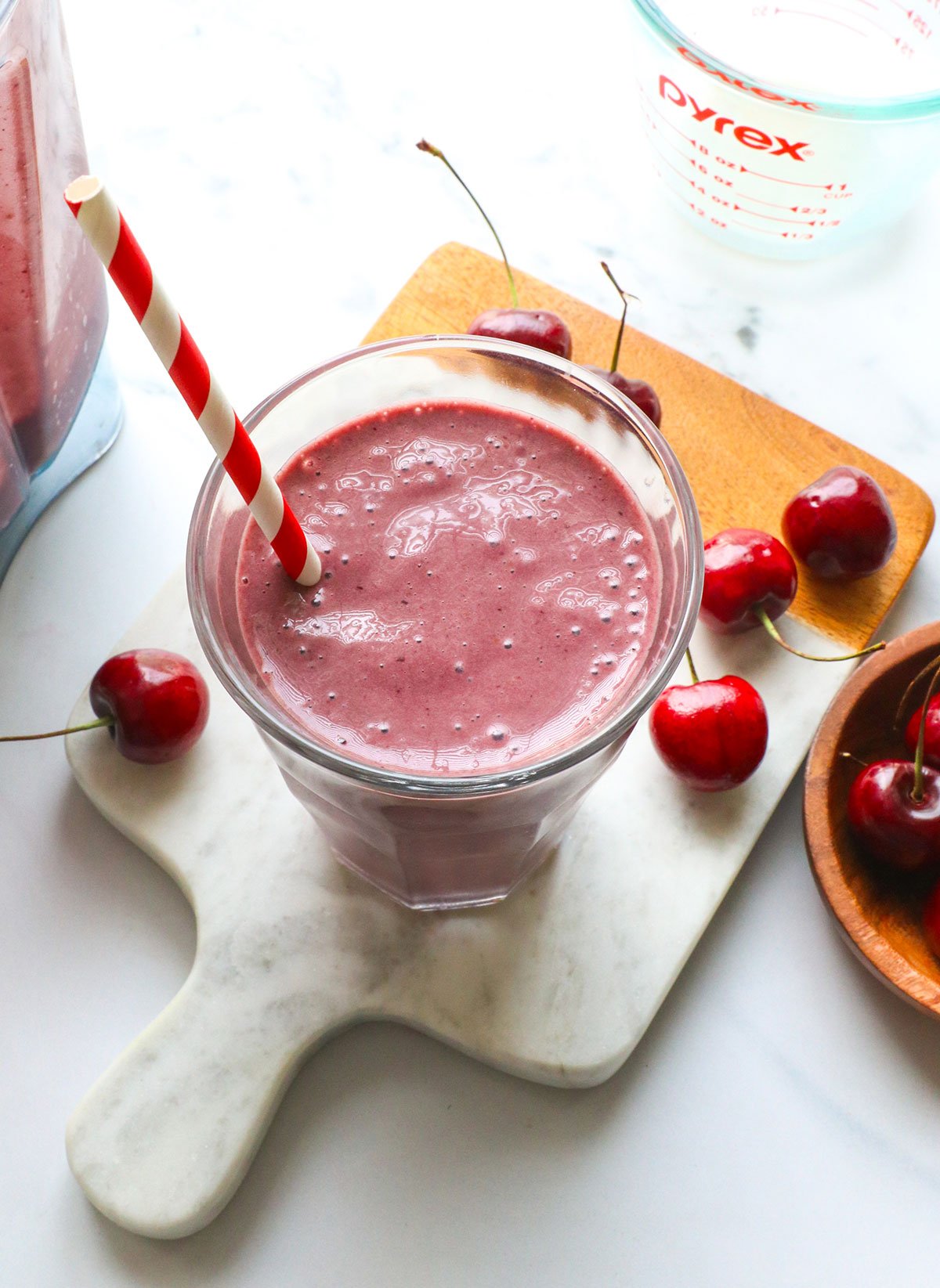 cherry smoothie in a glass with a straw. 