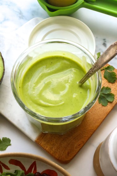 creamy avocado dressing in a glass jar with a spoon.