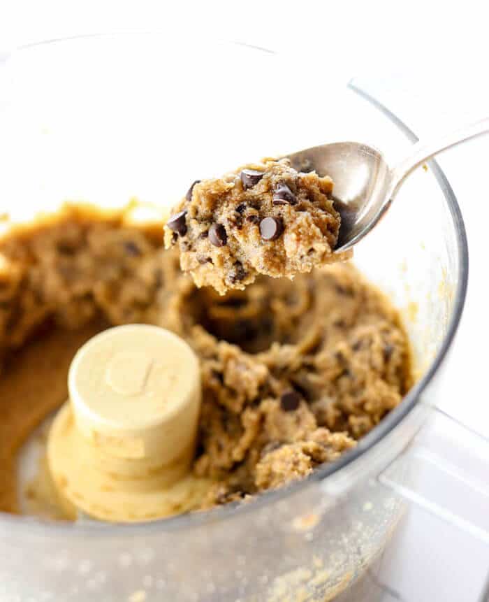 edible cookie dough on spoon with food processor in background