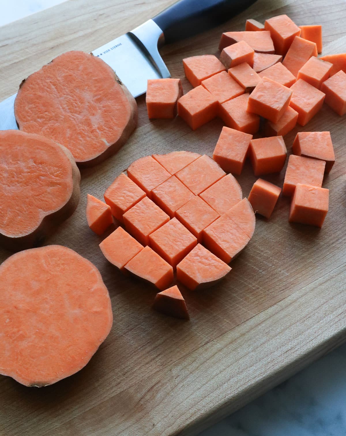 sweet potato cut into cubes on a cutting board. 