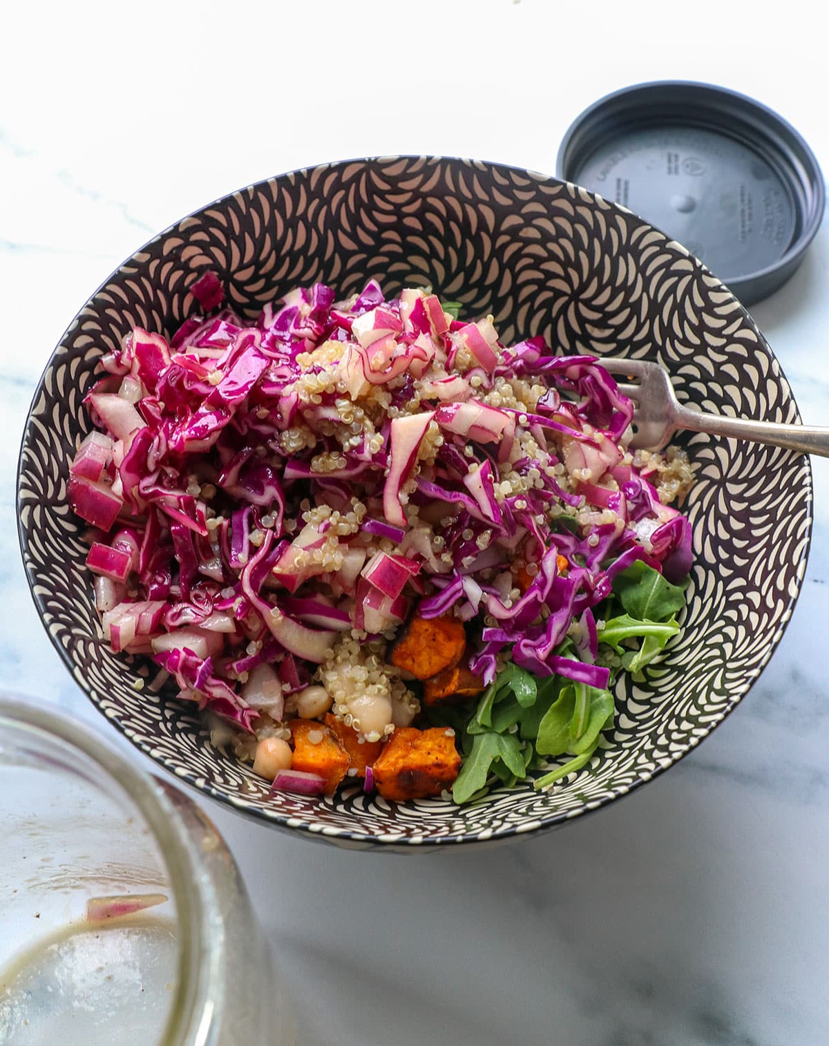 mason jar salad poured into a big serving bowl with the cabbage and red onion on top. 