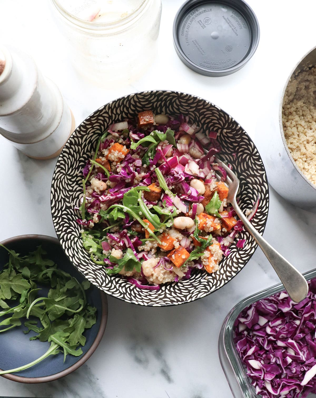 mason jar salad poured into a serving bowl with purple cabbage and white beans. 