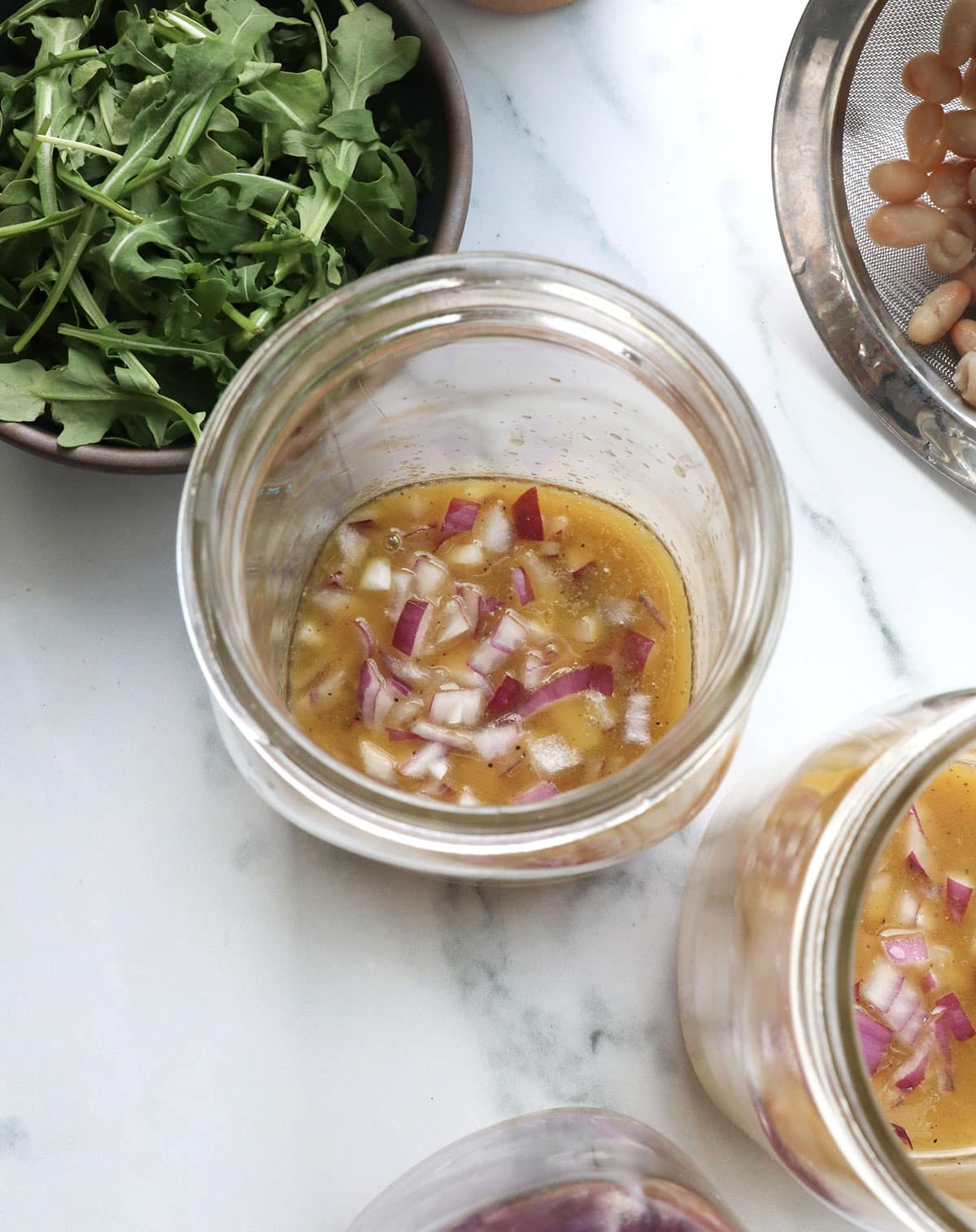 red onion sitting in a jar with apple cider vinaigrette for salad. 