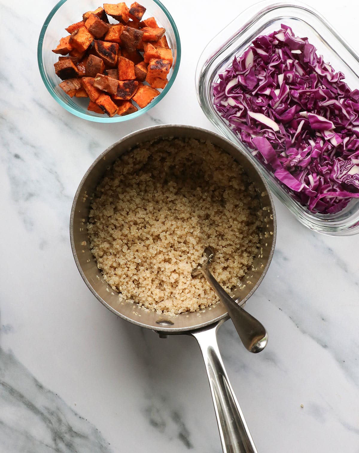 cooked quinoa in a silver pan near cabbage and sweet potatoes. 