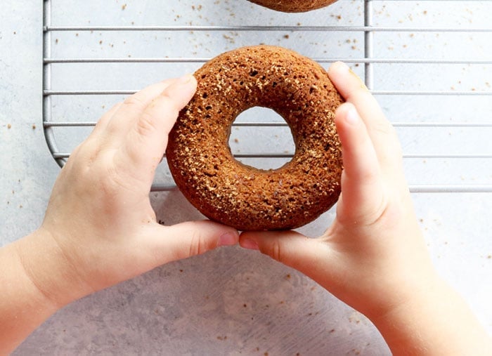 child's hands holding a baked donut