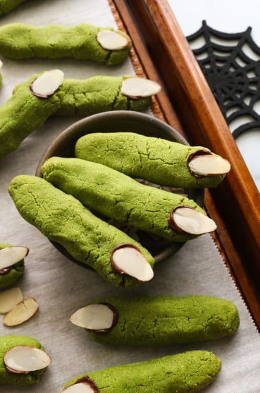 three green witch finger cookies in a bowl.