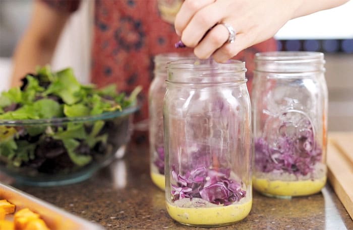 prep image of mason jar salad with cabbage and dressing layered on bottom