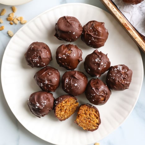 chocolate covered peanut butter balls on a white plate with one cut in half.