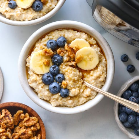 Two bowls of oatmeal topped with fruit next to an Instant Pot.