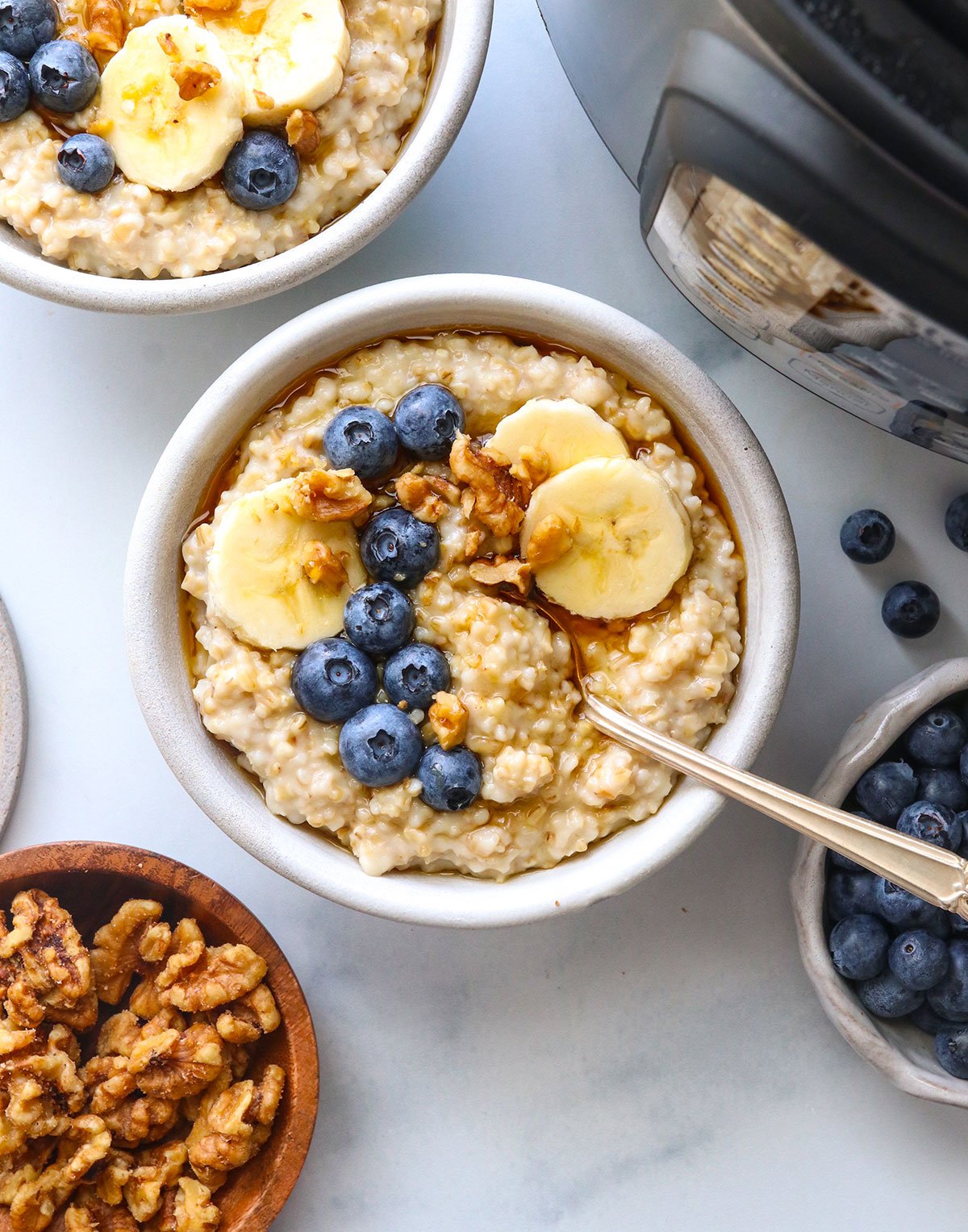 Two bowls of oatmeal topped with fruit next to an Instant Pot. 