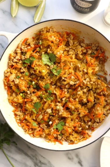 spaghetti squash and chicken stir fry in a white skillet.