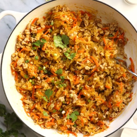 spaghetti squash and chicken stir fry in a white skillet.