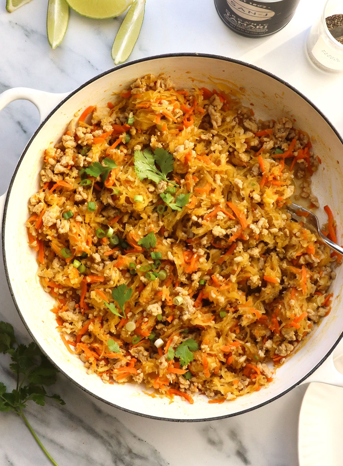 spaghetti squash and chicken stir fry in a white skillet.