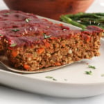 vegan meatloaf sliced and lifted with a serving spatula. Labeled for Pinterest.