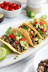 three vegan tacos on a plate with toppings