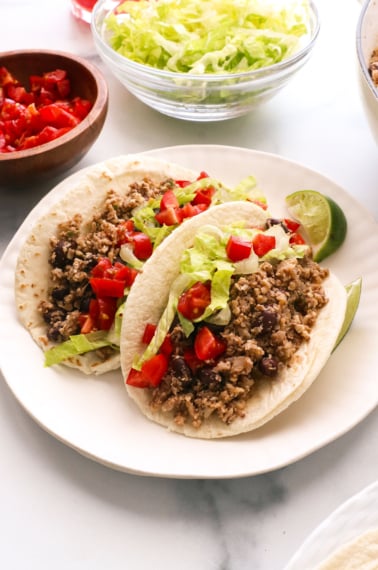 vegan tacos served with lettuce and tomato on a plate.