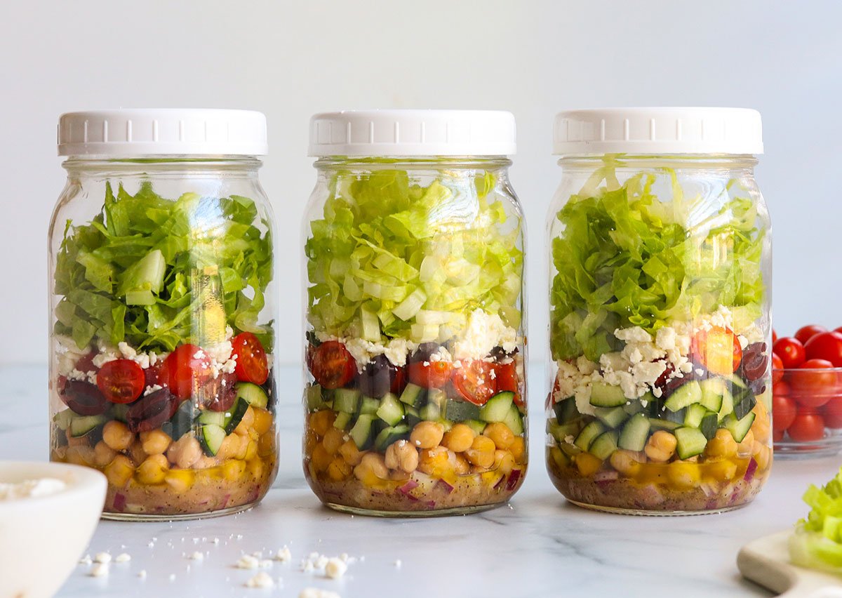 Three Mason jar salads with lids on top.