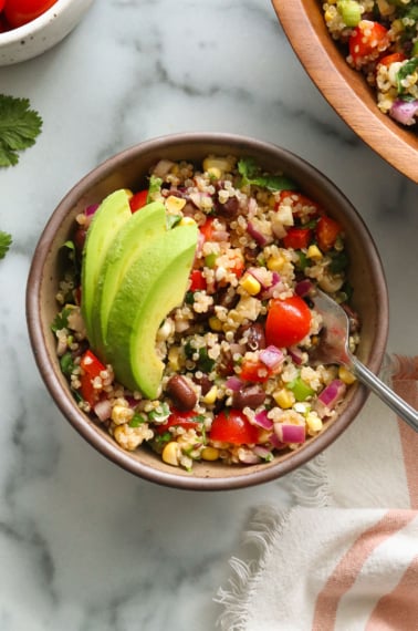 quinoa black bean salad bowl topped with avocado.