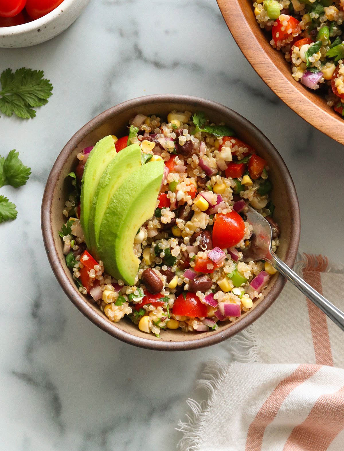 quinoa black bean salad bowl topped with avocado.
