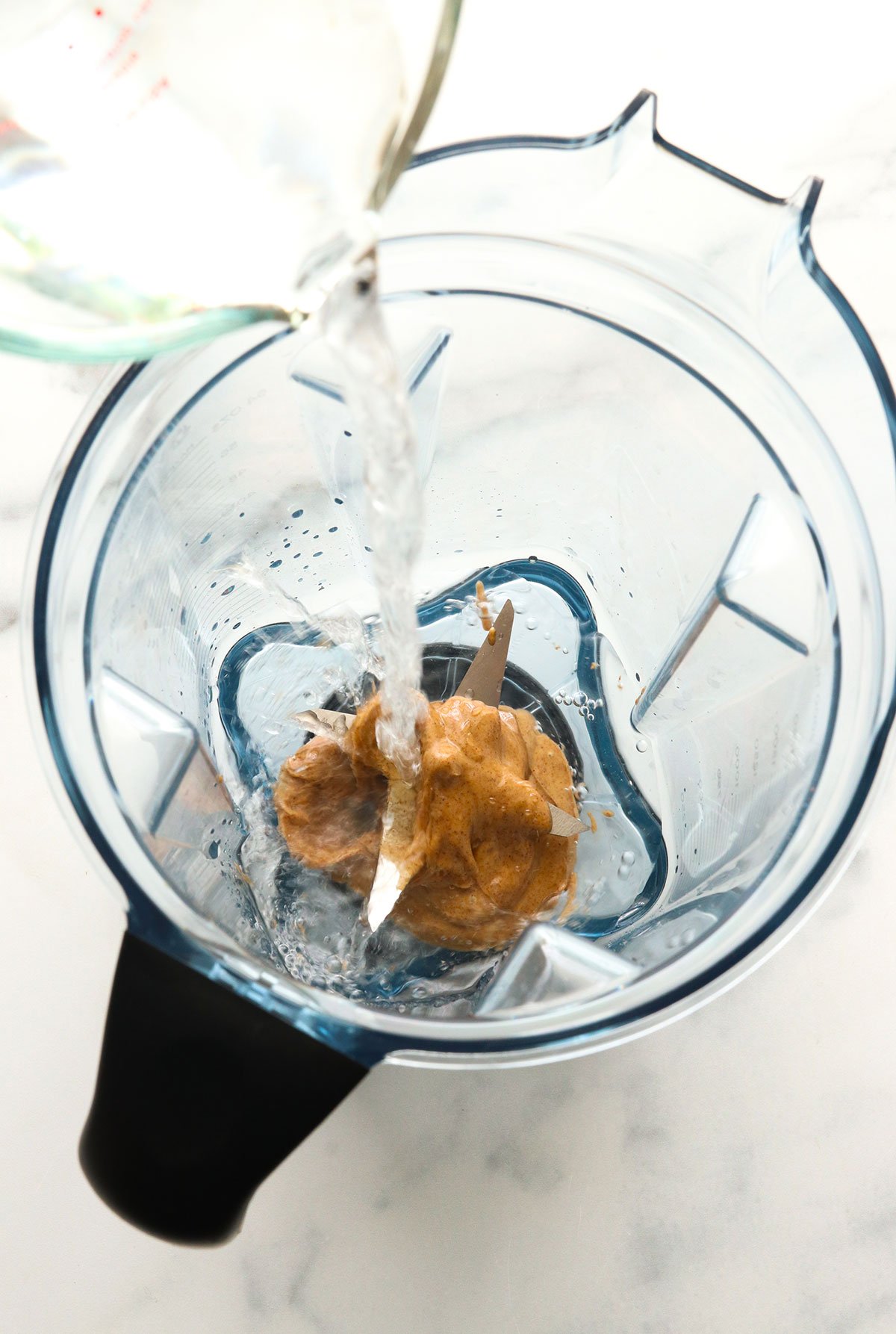 almond butter and water poured into a blender.