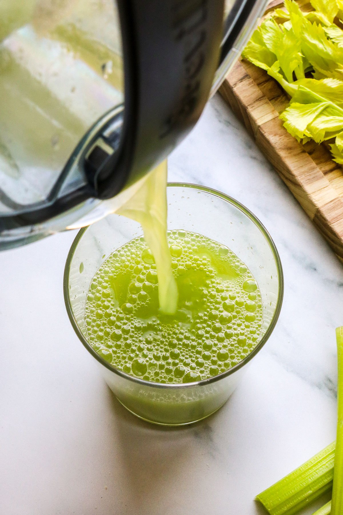 celery juice poured into glass from juicer.
