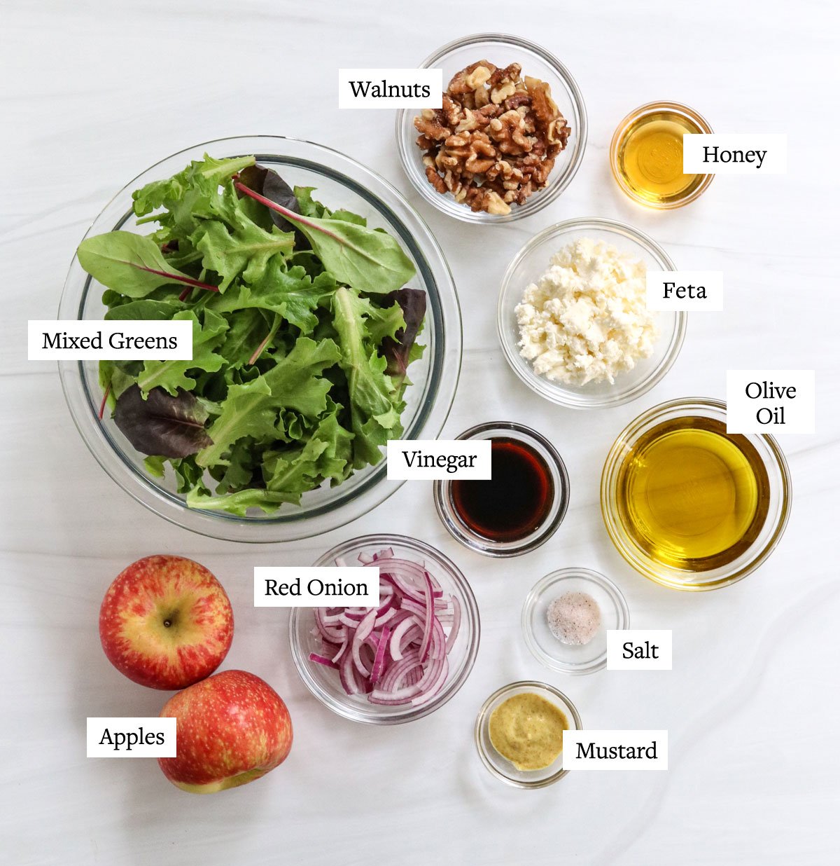 apple walnut salad ingredients labeled in glass bowls.