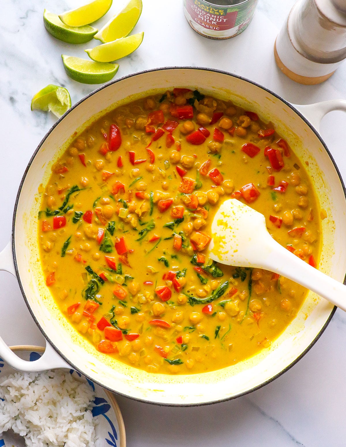 spinach wilted in the coconut curry sauce in a white pan.