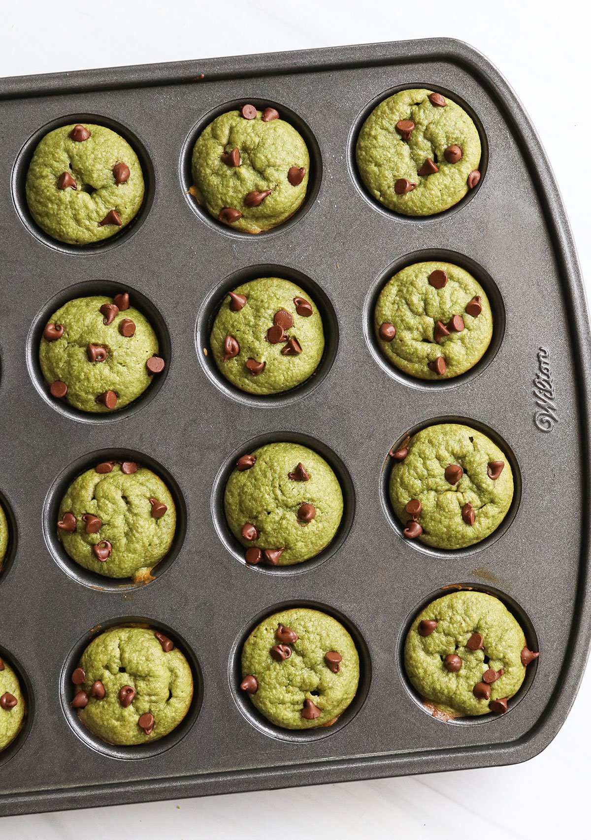spinach muffins with mini chocolate chips on top in pan.