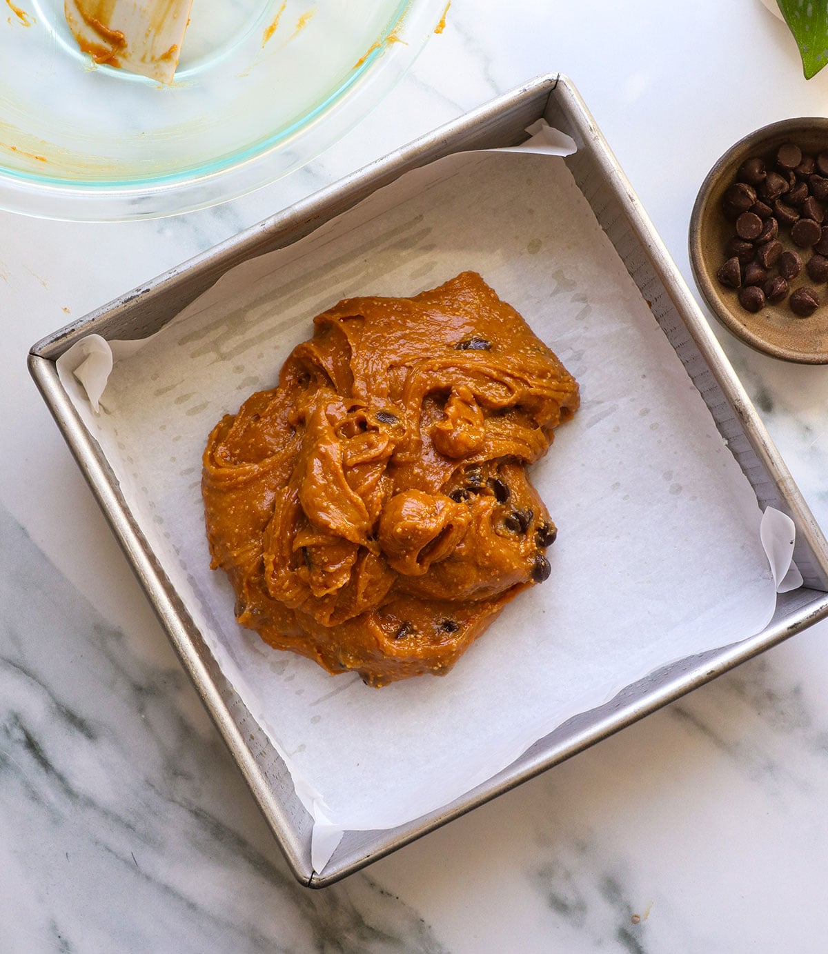 blondie batter plopped into the prepared pan with chocolate chips.