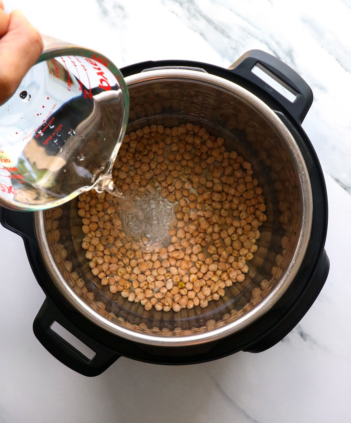 water poured into an instant pot with dried chickpeas. 