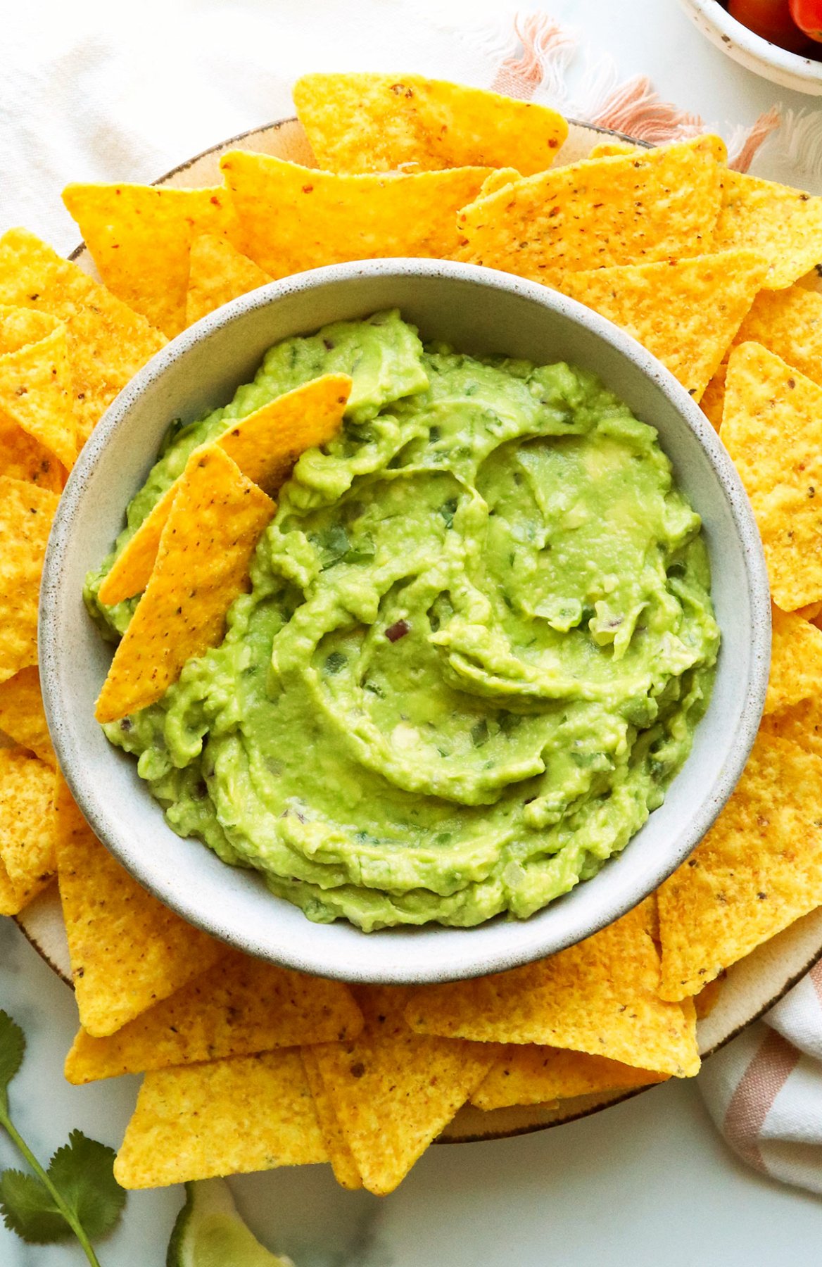 Closeup of the best guacamole served in a bowl with yellow corn chips.