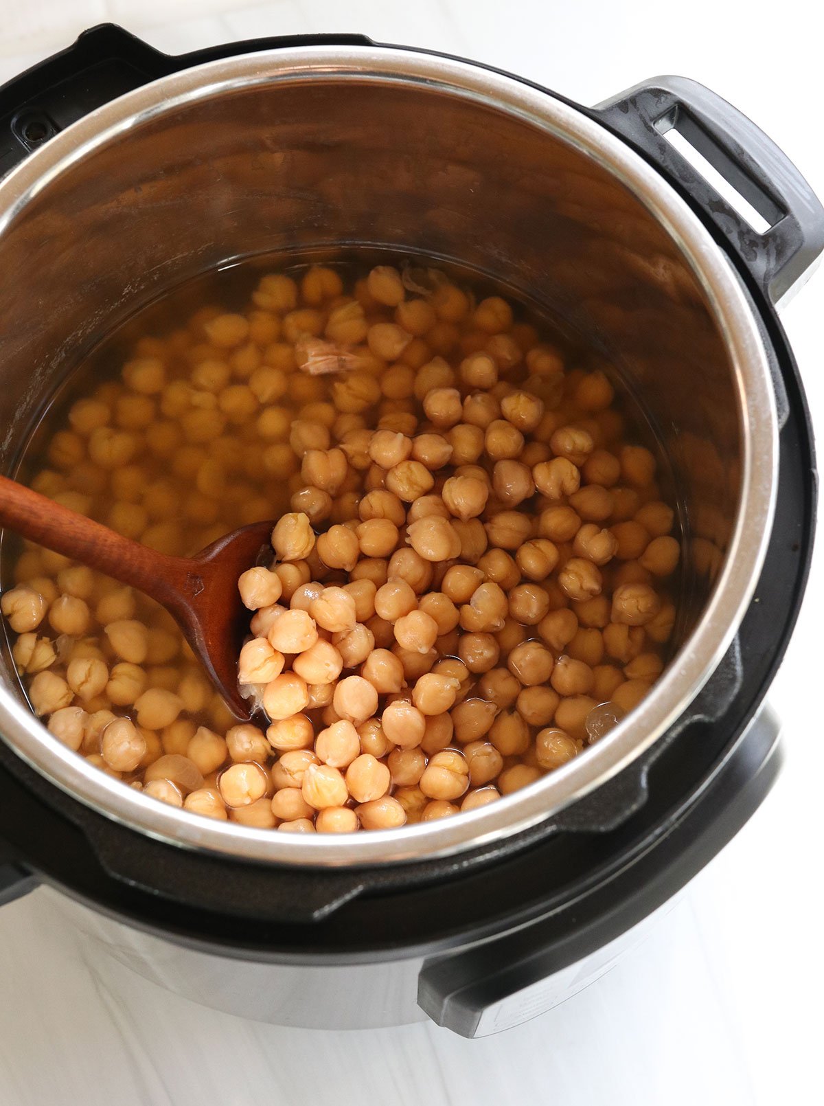 cooked chickpeas in the instant pot with wooden spoon.