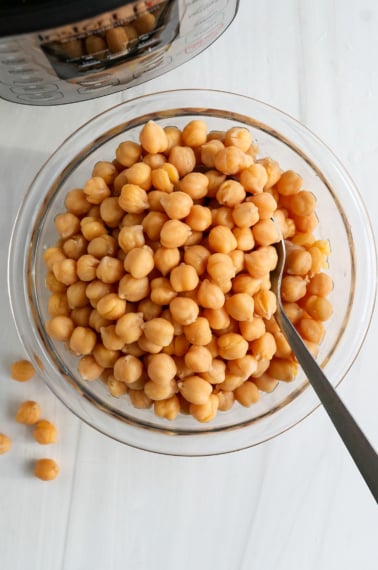 instant pot chickpeas in a glass bowl with spoon.