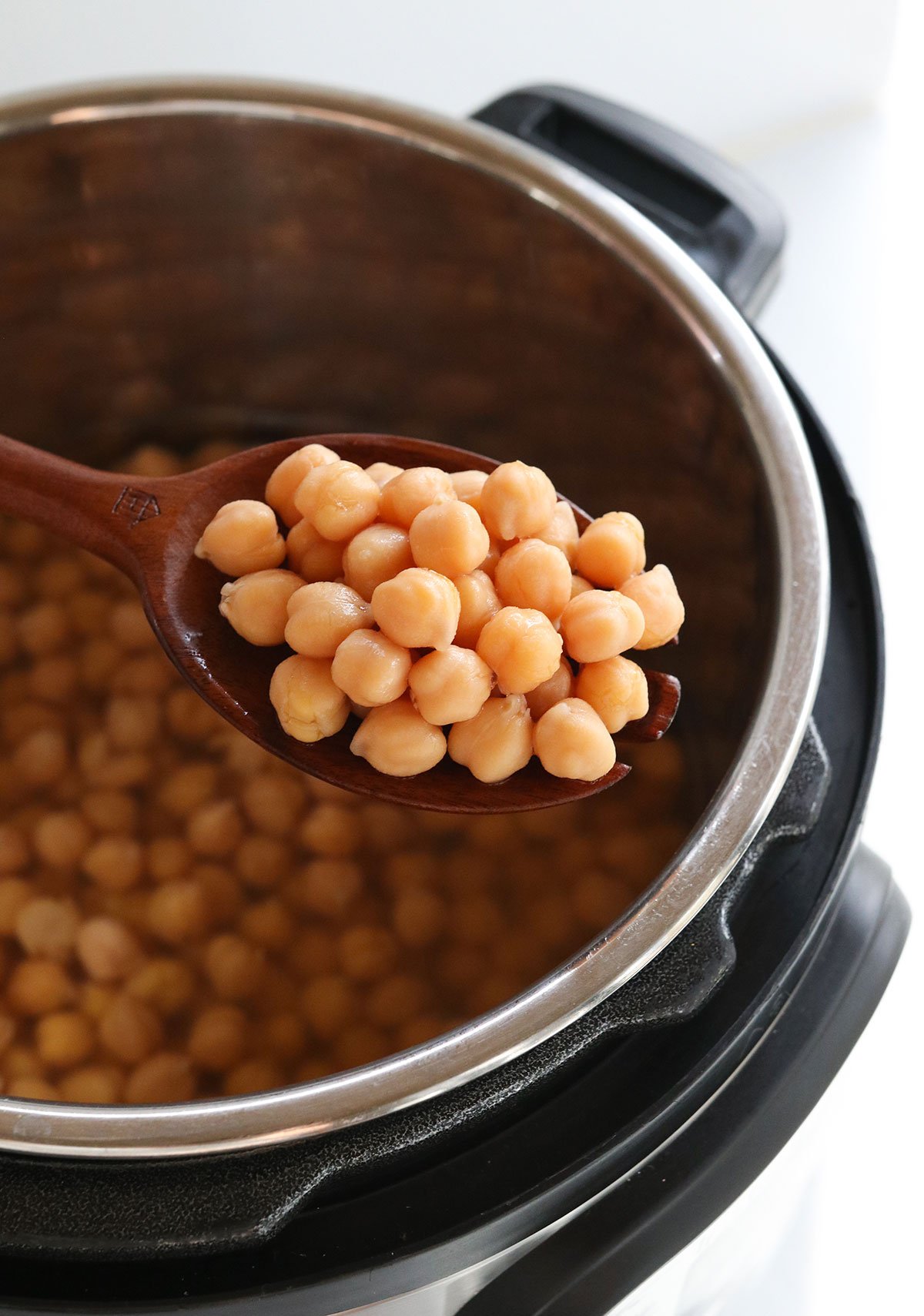 instant pot chickpeas lifted up on wooden spoon.